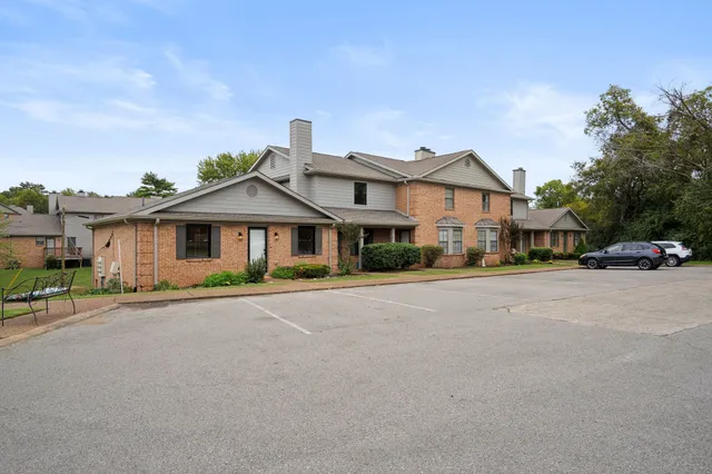 a front view of a house with a yard and car parked