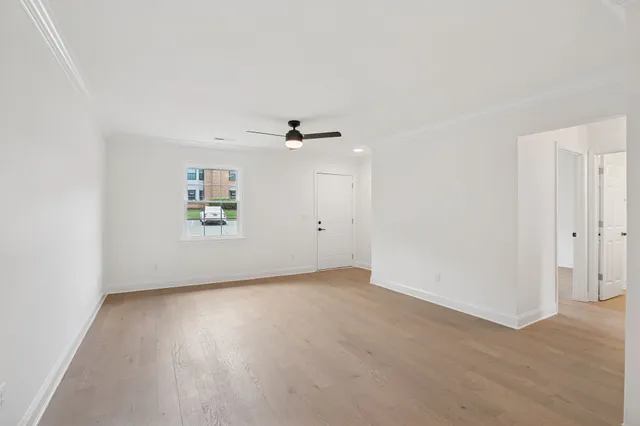 a view of an empty room with wooden floor and a window