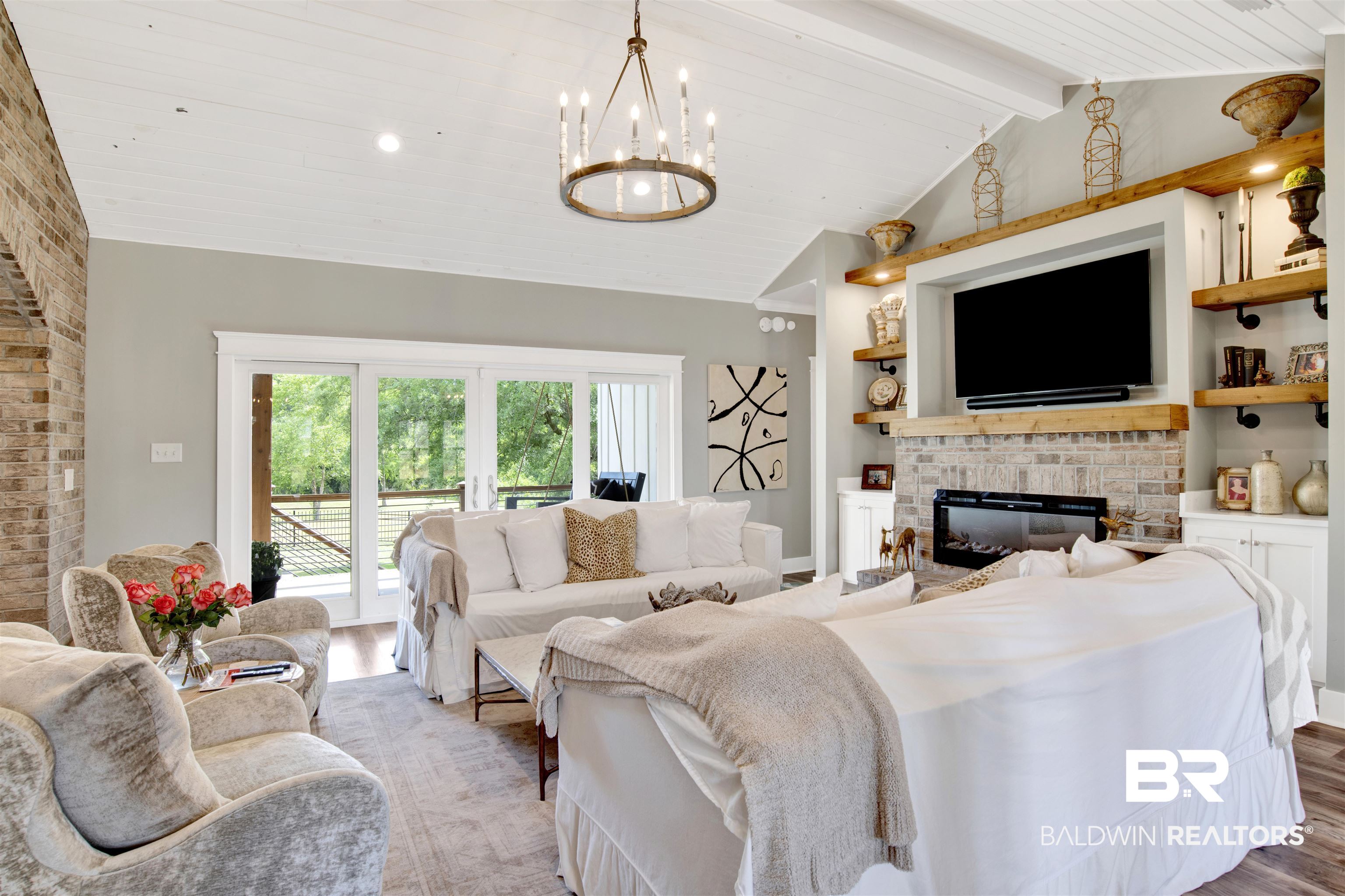 21621 Veranda Boulevard Fairhope, AL 36532 - Photo 27 of 51 Living area featuring lofted ceiling with beams, light wood finished floors, a brick fireplace, and a notable chandelier