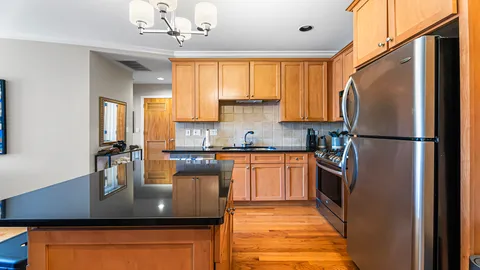 a kitchen with stainless steel appliances granite countertop a refrigerator a sink dishwasher a stove with wooden cabinets and floor