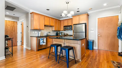 a kitchen with stainless steel appliances granite countertop a refrigerator a stove a sink dishwasher and a dining table with wooden floor