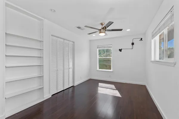 a view of empty room with wooden floor and fan
