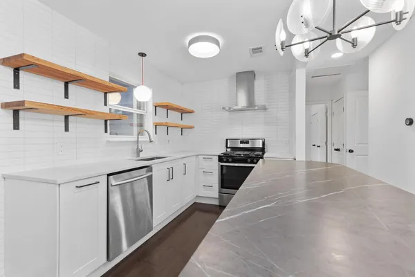 a kitchen with stainless steel appliances a sink a stove and cabinets