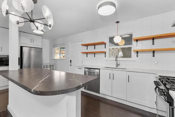 a room with stainless steel appliances granite countertop a sink a stove and a window