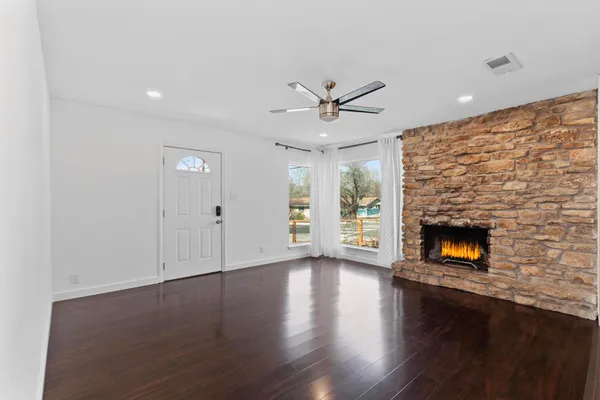 a view of a livingroom with wooden floor a fireplace and window