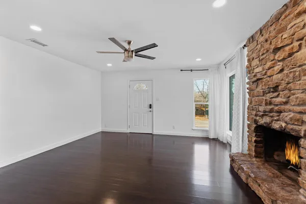 a view of a livingroom with wooden floor a ceiling fan and a window