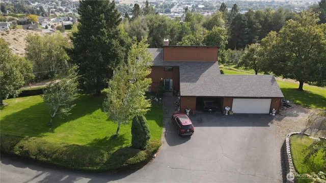an aerial view of a house with swimming pool and trees in the background