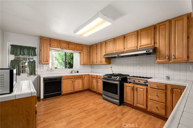 a kitchen with stainless steel appliances granite countertop wooden cabinets a stove top oven a sink and dishwasher