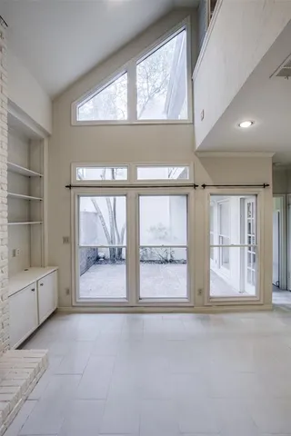 an empty room with large windows and chandelier
