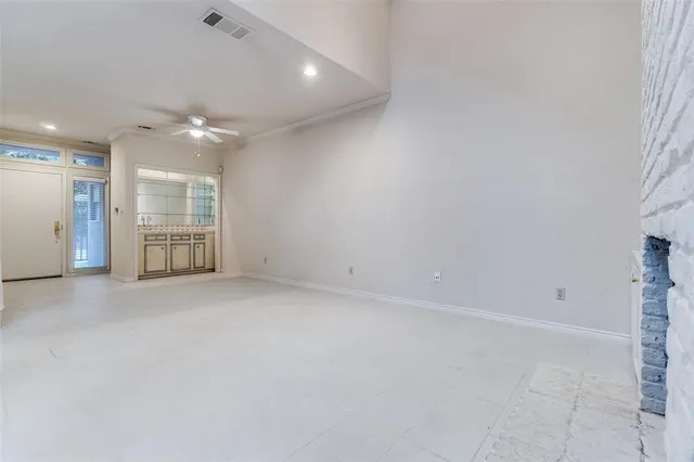 an empty room with chandelier fan and windows