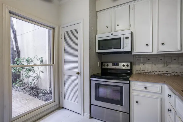 a kitchen with stainless steel appliances granite countertop white cabinets and a stove top oven