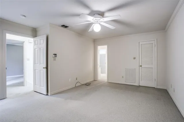 an empty room with chandelier fan and closet area