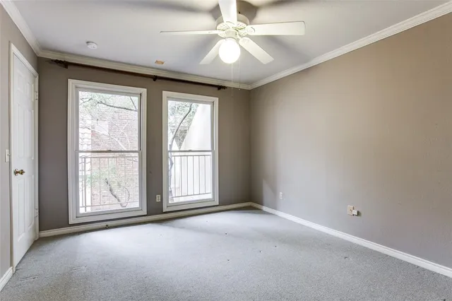an empty room with windows and chandelier fan