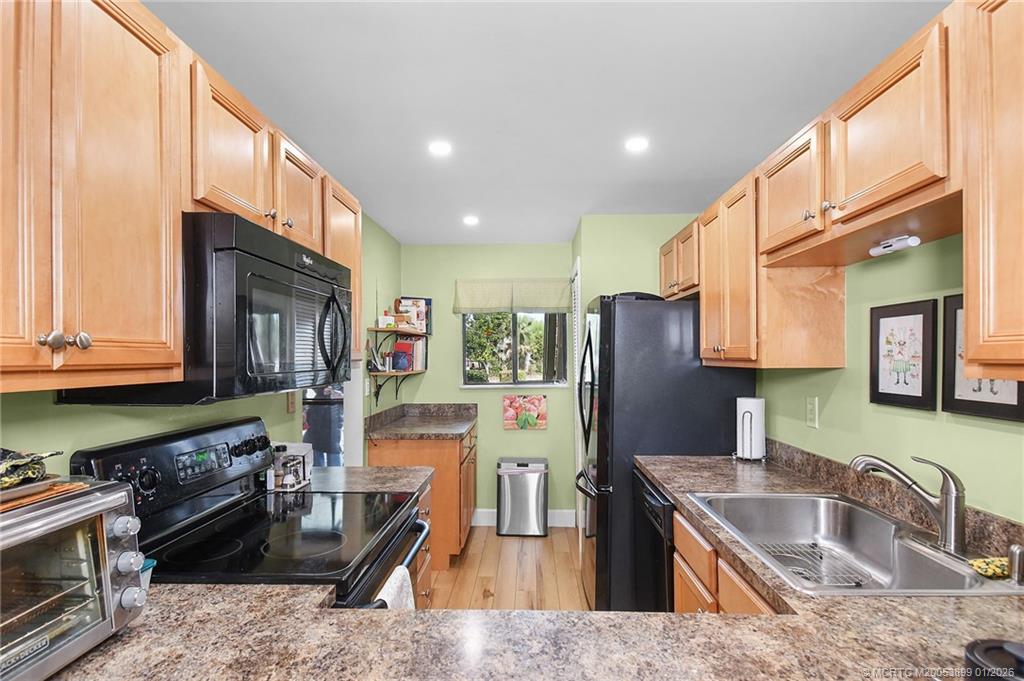 5403 Southeast Miles Grant Road, Unit H111 Stuart, FL 34997 - Photo 12 of 57 a kitchen with stainless steel appliances granite countertop a refrigerator a stove and a sink with wooden cabinets