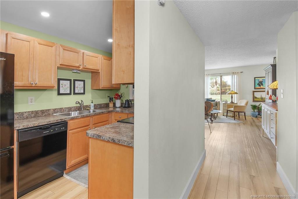 5403 Southeast Miles Grant Road, Unit H111 Stuart, FL 34997 - Photo 15 of 57 a kitchen with granite countertop wooden floors and stainless steel appliances