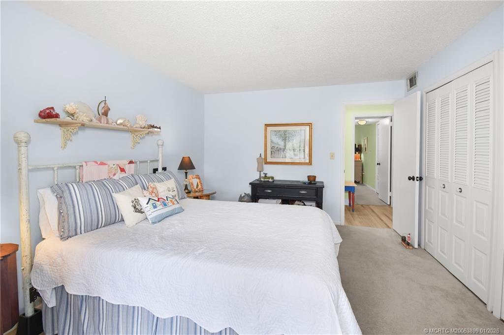 5403 Southeast Miles Grant Road, Unit H111 Stuart, FL 34997 - Photo 23 of 57 a bedroom with a bed and a chandelier