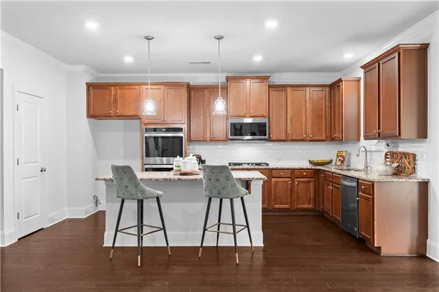 a kitchen with stainless steel appliances granite countertop a stove top oven a sink and a refrigerator