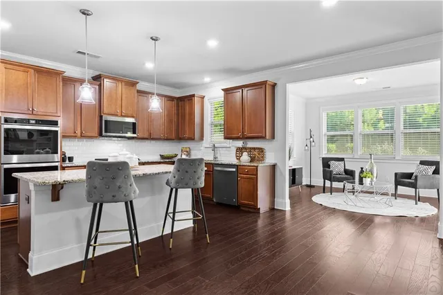 a kitchen with stainless steel appliances granite countertop a stove top oven a sink a dining table and chairs with wooden floor