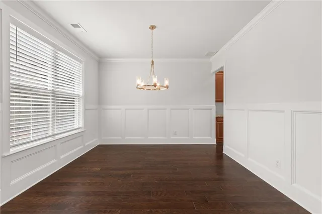 a view of an empty room with wooden floor fridge and a window