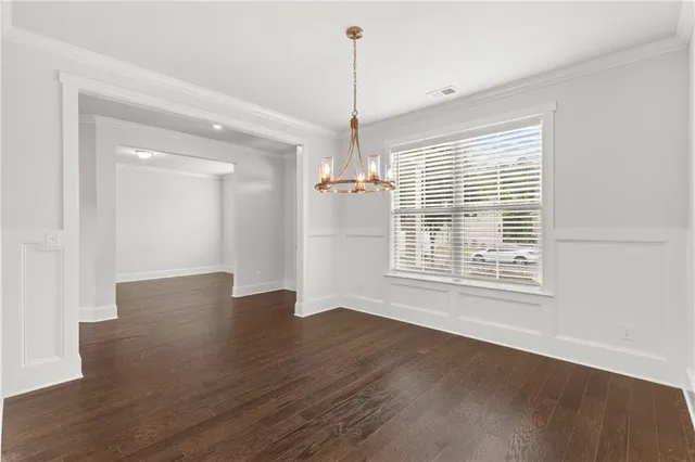 a view of an empty room with wooden floor and windows