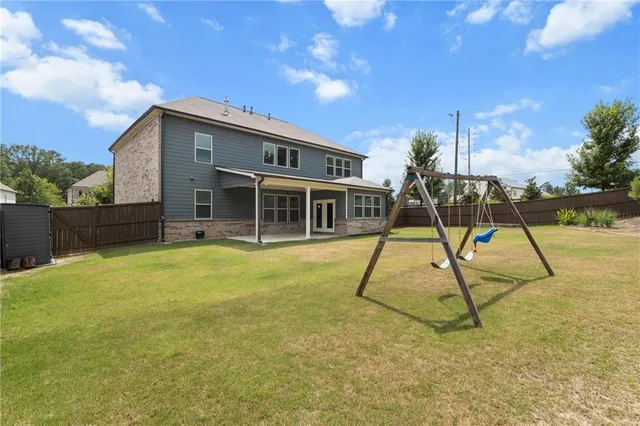 a house with a slide trees and wooden fence