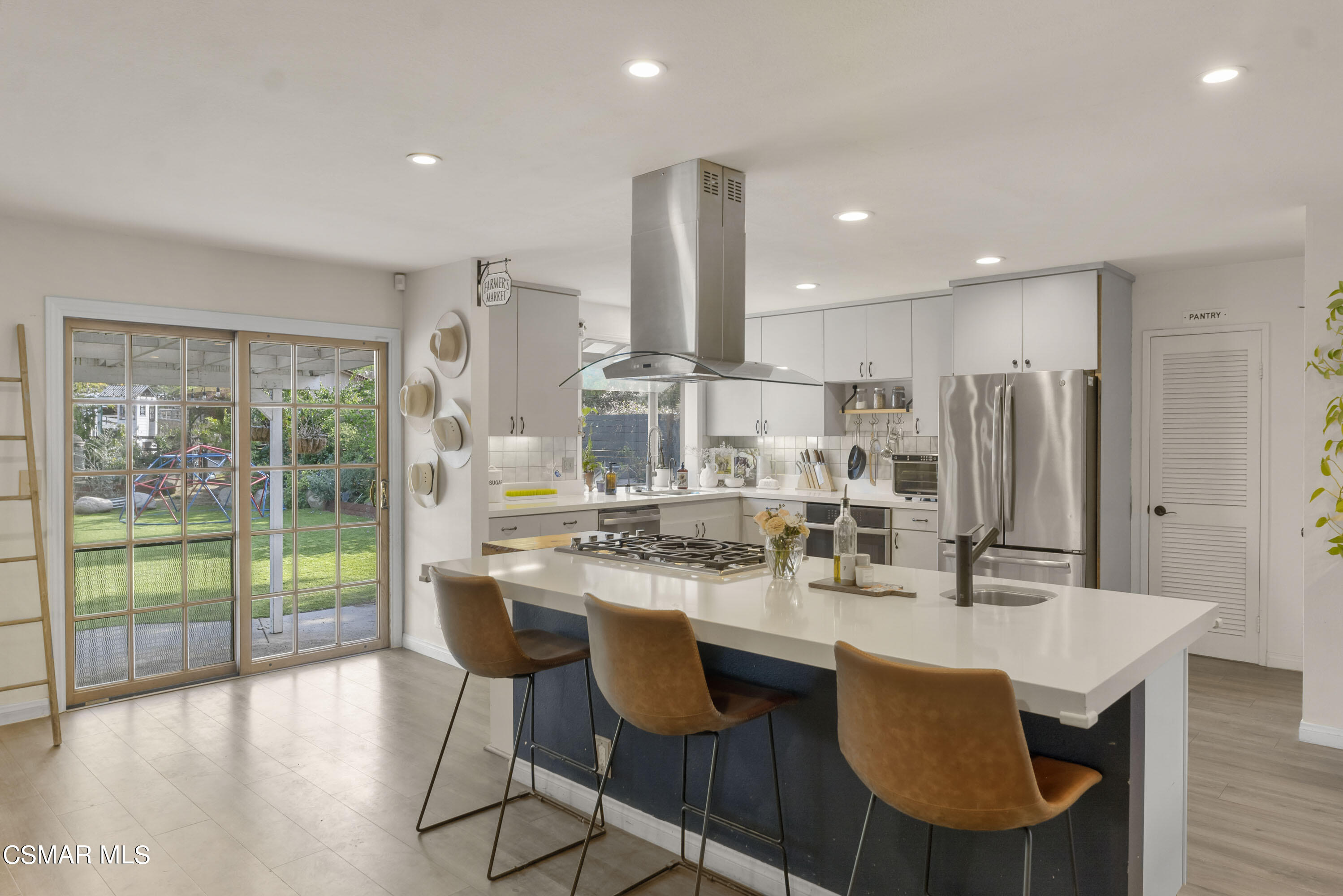 1065 Rambling Road Simi Valley, CA 93065 - Photo 5 of 54 a kitchen with stainless steel appliances kitchen island granite countertop a dining table chairs and wooden floor