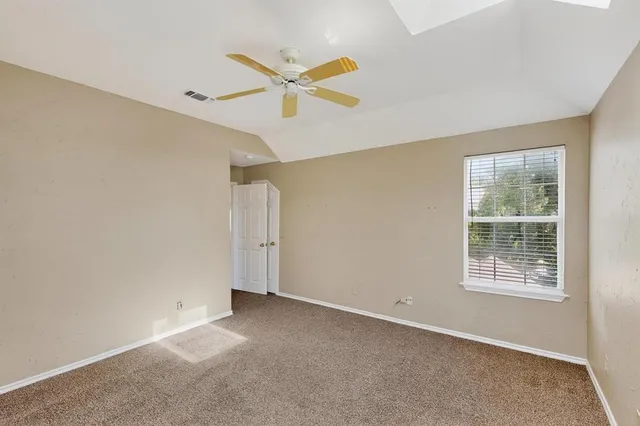 an empty room with ceiling fan and window