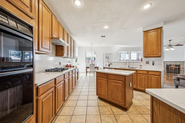a large kitchen with stainless steel appliances granite countertop a stove top oven a sink dishwasher and white cabinets