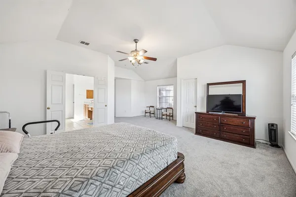 a spacious bedroom with a bed and a flat screen tv