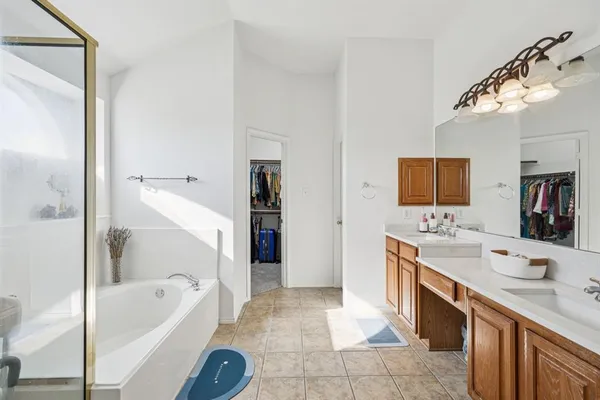 a spacious bathroom with a tub sink and mirror