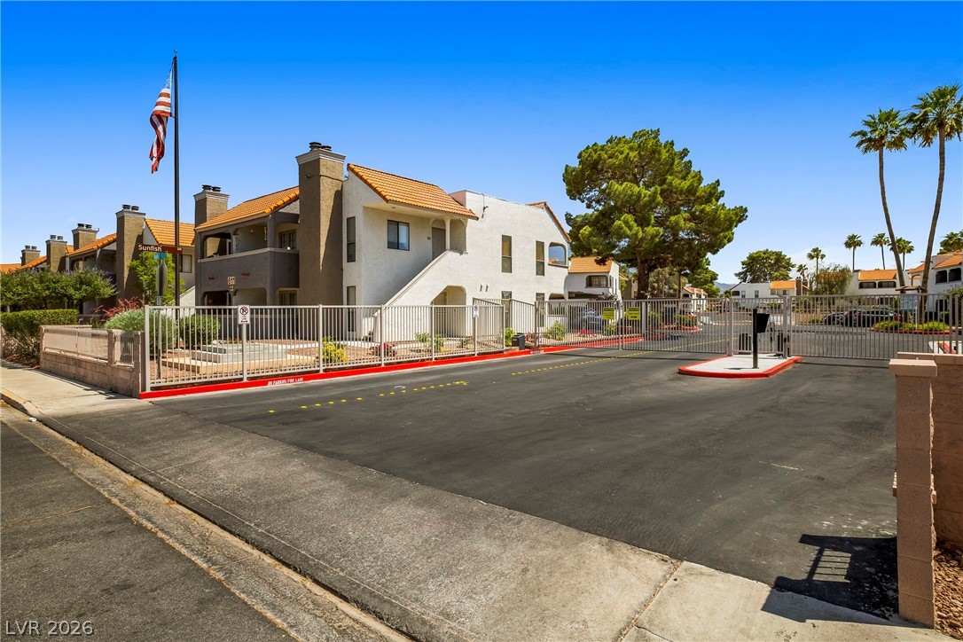 3311 Sunfish Drive, Unit D Henderson, NV 89014 - Photo 20 of 21 Secure community entrance with an automated gate and a paved driveway, framed by mature trees.