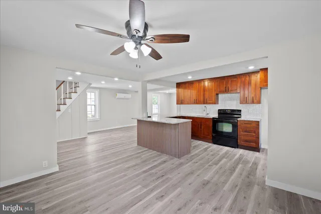 a kitchen with stainless steel appliances granite countertop a refrigerator a sink dishwasher a stove and a dining table with wooden floor