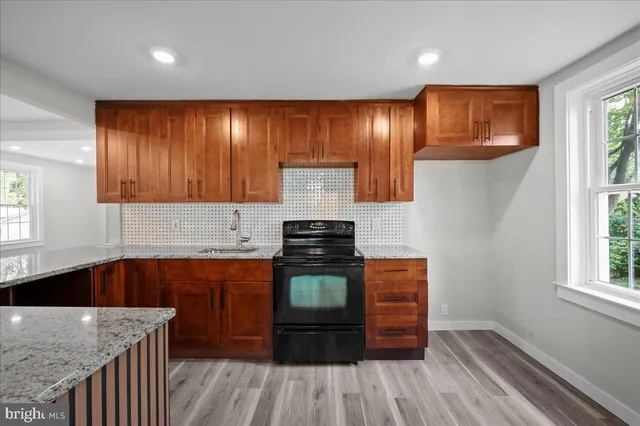 a kitchen with stainless steel appliances granite countertop wooden cabinets a stove and a sink