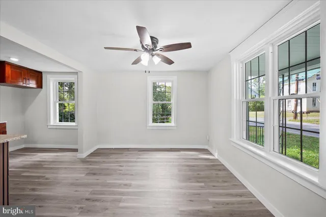 a view of empty room with wooden floor and fan