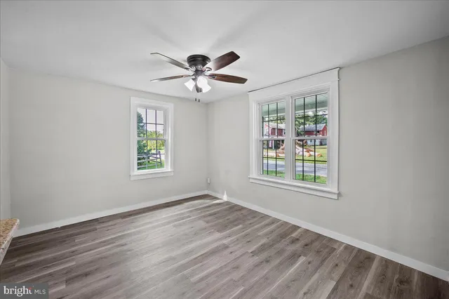 a view of an empty room with a window and wooden floor