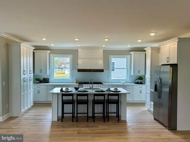 a kitchen with stainless steel appliances granite countertop a dining table chairs refrigerator and sink