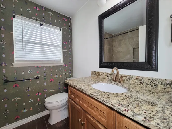 a bathroom with a granite countertop sink a toilet and mirror