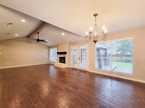 a view of a big room with wooden floor a chandelier and windows