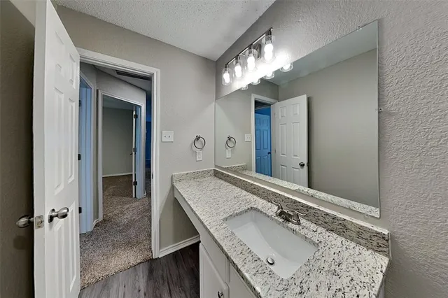 a bathroom with a granite countertop sink a large mirror and a wooden vanity