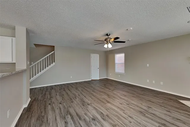 a view of an empty room with wooden floor and fan