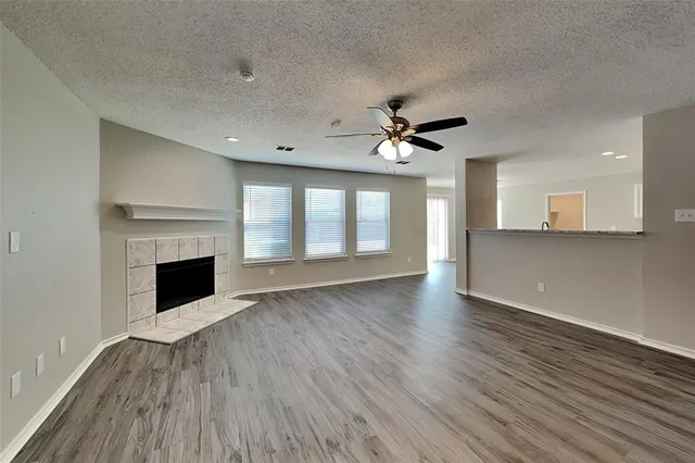 a view of an empty room with wooden floor and a fireplace