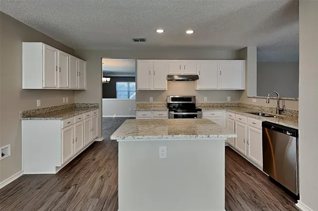 a kitchen with a stove a sink a microwave a counter space and cabinets