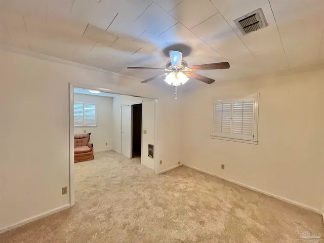 an empty room with chandelier fan and windows