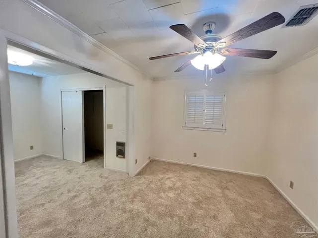 an empty room with closet and a chandelier fan