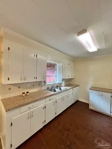 a large kitchen with a lot of counter space and wooden floor