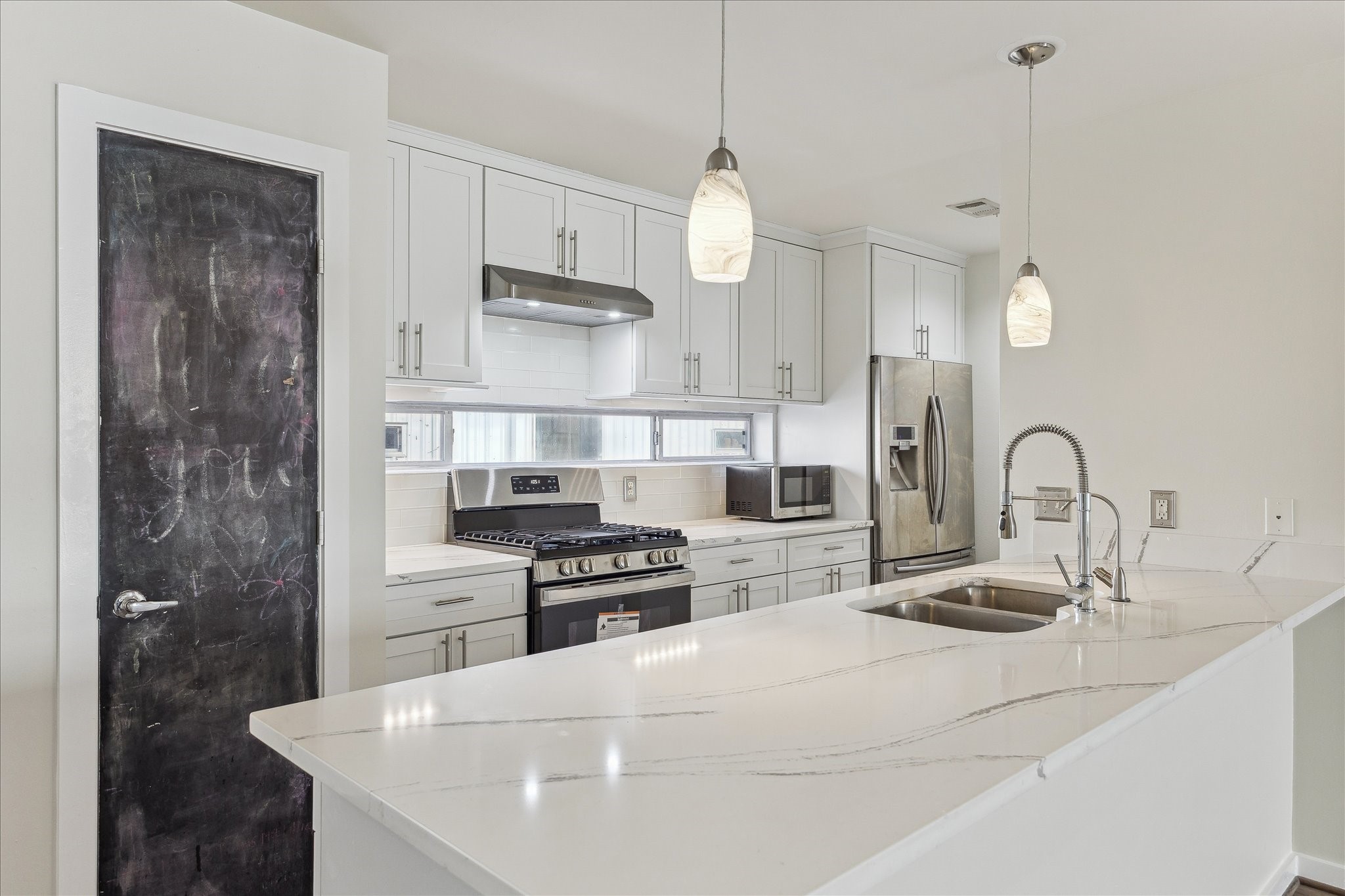 1617 Tuam Street Houston, TX 77004 - Photo 2 of 35 Modern kitchen with quartz counters, stainless-steel appliances, and custom cabinetry. Large island offers additional seating and prep space.