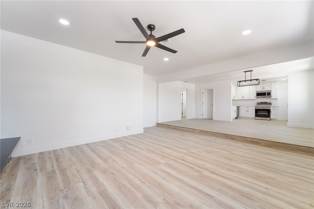 39 Lowery Street Henderson, NV 89015 - Photo 4 of 40 A spacious, open-concept living area with light wood flooring flows seamlessly into a contemporary kitchen.