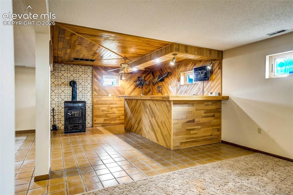 7585 Ponca Road Colorado Springs, CO 80908 - Photo 29 of 49 wet bar, wood burning ceramic stove, tiled flooring