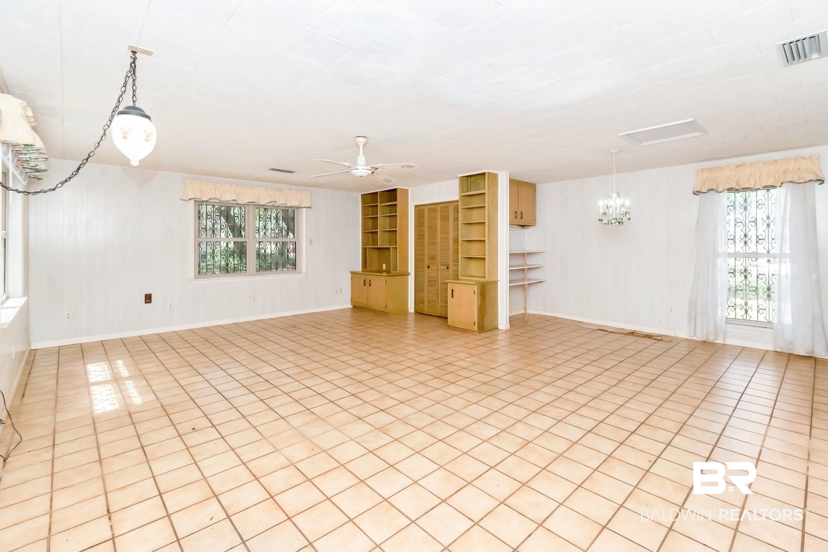 3715 South Conway Drive Mobile, AL 36608 - Photo 5 of 24 Empty room with built in features, visible vents, a healthy amount of sunlight, and ceiling fan with notable chandelier