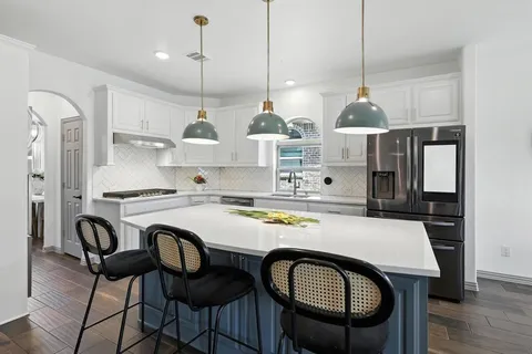 a kitchen with stainless steel appliances granite countertop a sink a stove a refrigerator and island with wooden floor